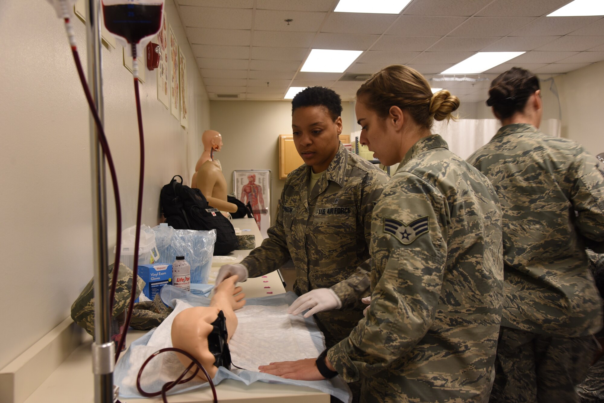 Senior Airmen Erica Johnson and Katie Cunningham, 403rd Aeromedical Staging Squadron medical technicians, work together and practice starting an IV during the escape room scenario, which was used to maintain the training requirements for medical technicians during the March Unit Training Assembly at Keesler Air Force Base.  The medical technicians had to work together to "save the life" of their patient during the training before they could escape. (U.S. Air Force photo by Jessica L. Kendziorek)