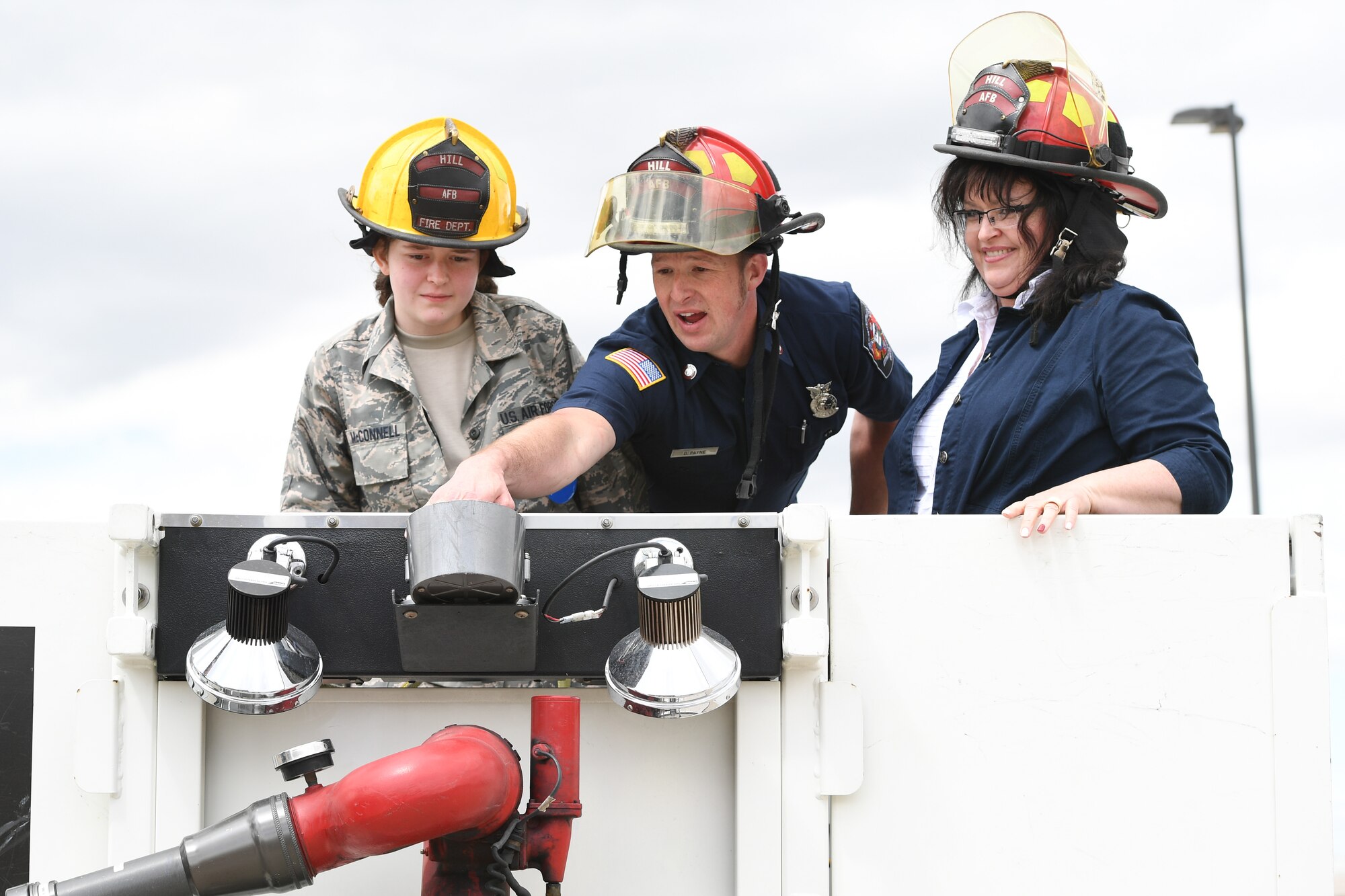 Captain Daniel Payne, 775th Civil Engineering Squadron Firefighter, demonstrates how to communicate with him to Michelle McConnell and her mother, Andrea McConnell before taking a ride up in the firetruck bucket April 22, 2019 at Hill Air Force Base, Utah. Michelle was granted her wish to be Airman of the day by Make-A-Wish Utah and 75th Air Base Wing at Hill. (U.S. Air Force Photo by Cynthia Griggs)