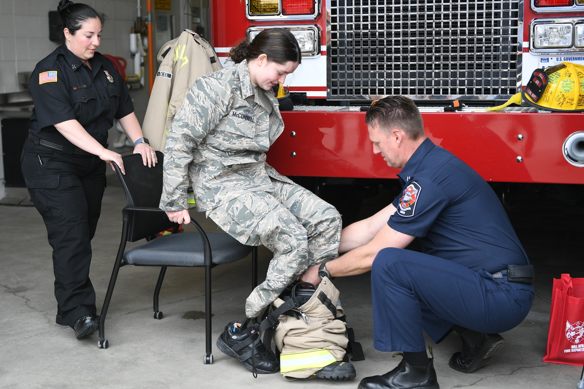 Captain John Rice, 775th Civil Engineering Squadron Firefighter, and Tiana Bykowski, 775th CES public information officer, help Michelle McConnell with her fire protection gear April 22, 2019 at Hill Air Force Base, Utah. Michelle was granted her wish to be Airman of the day by Make-A-Wish Utah and 75th Air Base Wing at Hill. (U.S. Air Force Photo by Cynthia Griggs)
