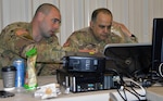 Chief Warrant Officer 2 Brian Gosch (left) off Milton, Washington, points out a network abnormality to Capt. Sameer Puri of Federal Way, Washington, during Cyber Shield 19 at Camp Atterbury, Ind., from April 5-19, 2019.
