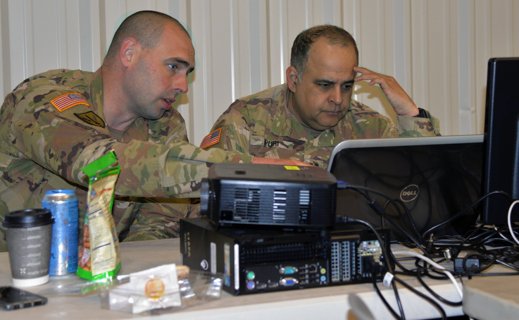 Chief Warrant Officer 2 Brian Gosch (left) off Milton, Washington, points out a network abnormality to Capt. Sameer Puri of Federal Way, Washington, during Cyber Shield 19 at Camp Atterbury, Ind., from April 5-19, 2019.