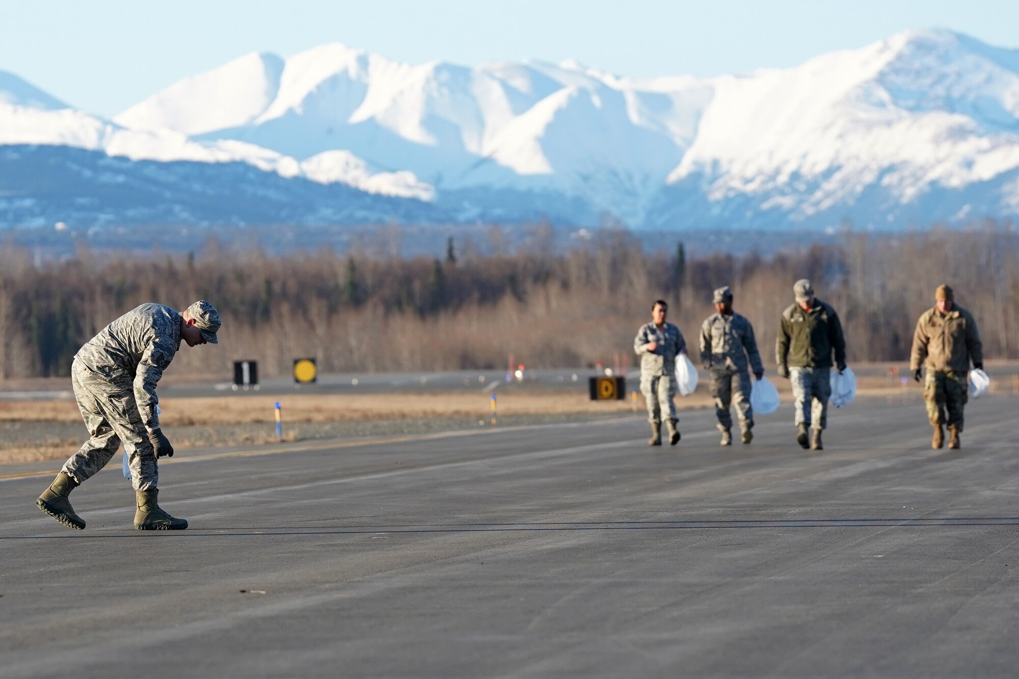 U.S. Airmen from the 3rd Wing, 176th Wing, and 477th Fighter Group conduct a foreign object debris walk on the flightline at Joint Base Elmendorf-Richardson, Alaska, April 26, 2019. The Airmen conducted the FOD walk to remove debris that could damage aircraft and hinder mission readiness.