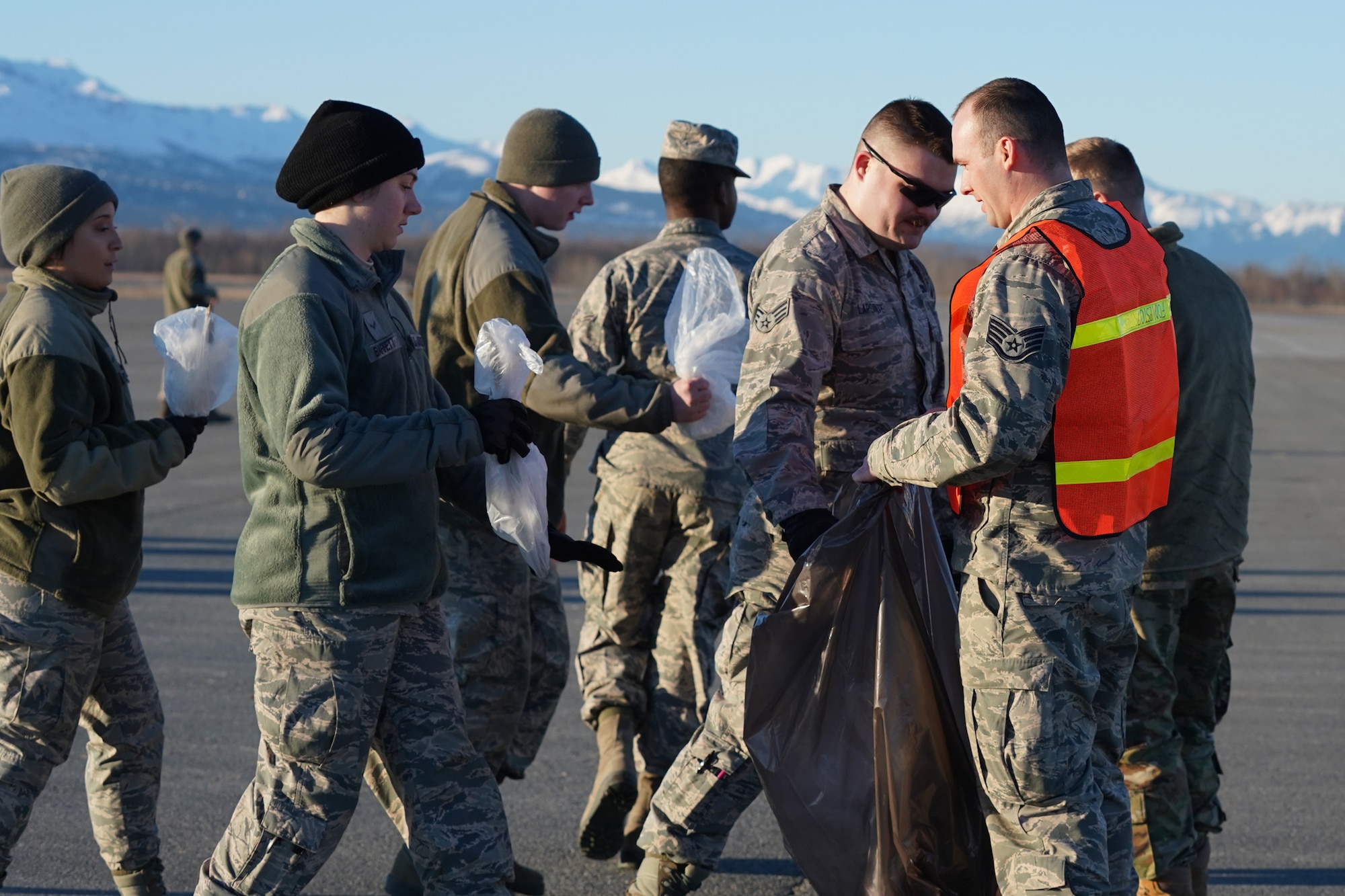 U.S. Airmen from the 3rd Wing, 176th Wing, and 477th Fighter Group conduct a foreign object debris walk on the flightline at Joint Base Elmendorf-Richardson, Alaska, April 26, 2019. The Airmen conducted the FOD walk to remove debris that could damage aircraft and hinder mission readiness.