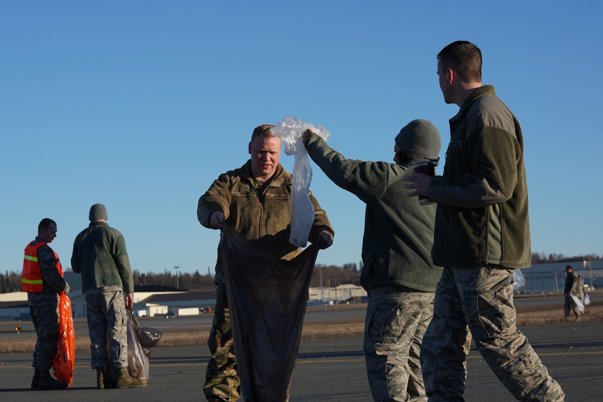 U.S. Airmen from the 3rd Wing, 176th Wing, and 477th Fighter Group conduct a foreign object debris walk on the flightline at Joint Base Elmendorf-Richardson, Alaska, April 26, 2019. The Airmen conducted the FOD walk to remove debris that could damage aircraft and hinder mission readiness.
