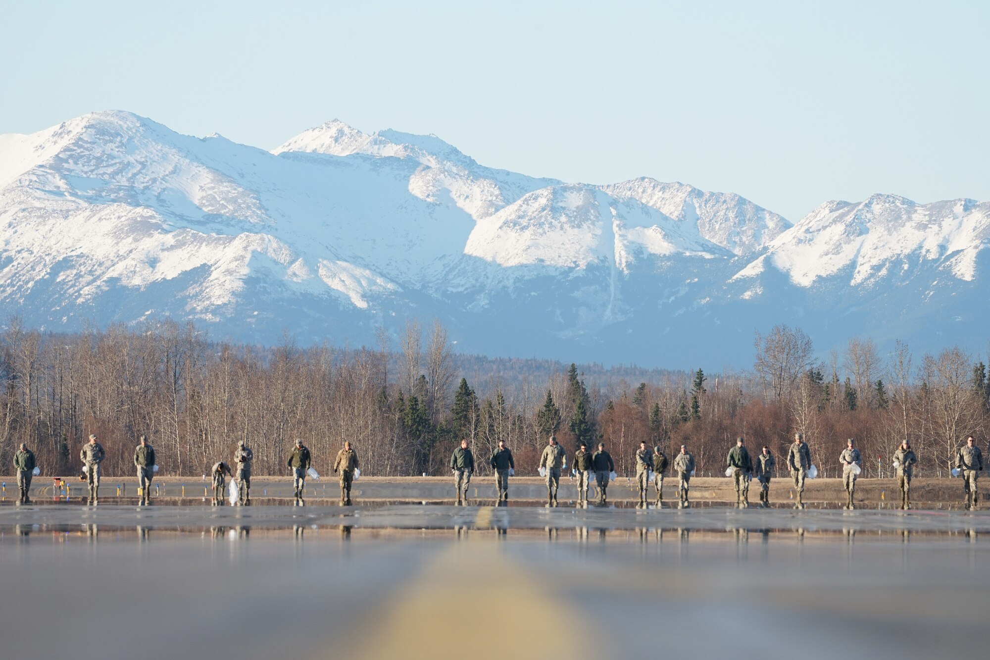 U.S. Airmen from the 3rd Wing, 176th Wing, and 477th Fighter Group conduct a foreign object debris walk on the flightline at Joint Base Elmendorf-Richardson, Alaska, April 26, 2019. The Airmen conducted the FOD walk to remove debris that could damage aircraft and hinder mission readiness.