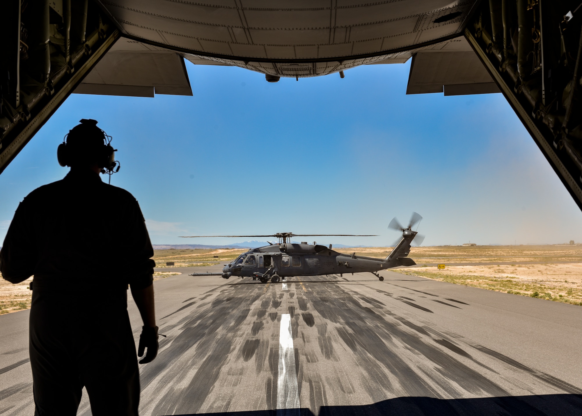 A loadmaster assigned to the 415th Special Operations Squadron, Kirtland Air Force Base, N.M., watches an HH-60G PAVE Hawk during a training mission at Belen Alexander Airport (Belen, N.M.), April 19, 2019. The Mission of the 512th RQS is to provide mission ready UH-1N Huey and HH-60G Pave Hawk crewmembers to Air Force Special Operations and Air Force Global Strike Command units world-wide. (U.S. Air Force photo by Airman 1st Class Austin J. Prisbrey)