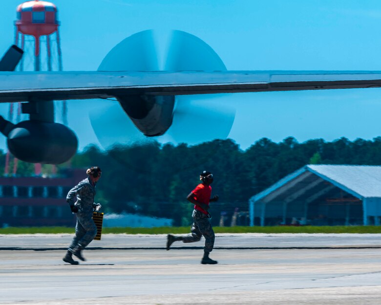 Tech. Sgt. Jeffrey Lawson, Airman First Class Antonio Yancy, air transportation specialist with the 96th Aerial Port Squadron, run past a C-130H during the engine running on-load/off-load event  of the Port Dawg Challenge, April 24, 2019.
