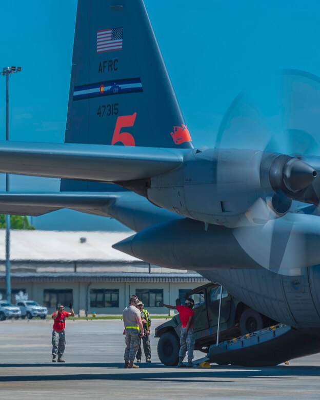 Tech. Sgt. Jose Vargas-Gonzalez and Airman First Class Antonio Yancy, 96th Aerial Port Squadron team members, spot a Humvee off the ramp of a  C-130H during the engine running on-load/off-load event of the Port Dawg Competition on April 23, 2019.