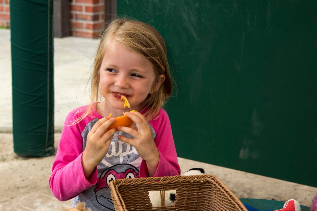 A child eats an orange during the Teddy Bear Picnic, April 26, 2019, at Moody Air Force Base, Ga. The Child Development Center hosted the event in support of the Month of the Military Child in April. (U.S. Air Force photo by Senior Airman Erick Requadt)