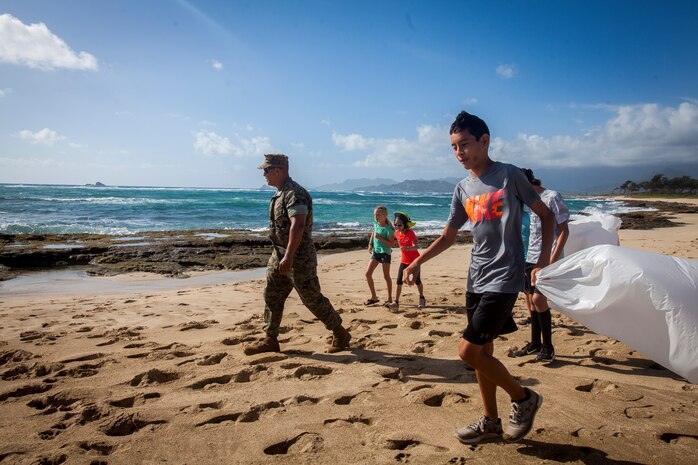 U.S. Marine Corps Staff Sgt. Jimmy Ortiz, a hazardous material/hazardous waste staff noncommissioned officer with Marine Corps Base Hawaii (MCBH) environmental, and students with Mokapu Elementary School look for trash and debris during an Earth Day beach clean-up, MCBH, Apr. 23, 2019. During the event, students and faculty with the school cleaned up Fort Hase beach by picking up trash and debris. (U.S. Marine Corps photo by Cpl. Matthew Kirk)
