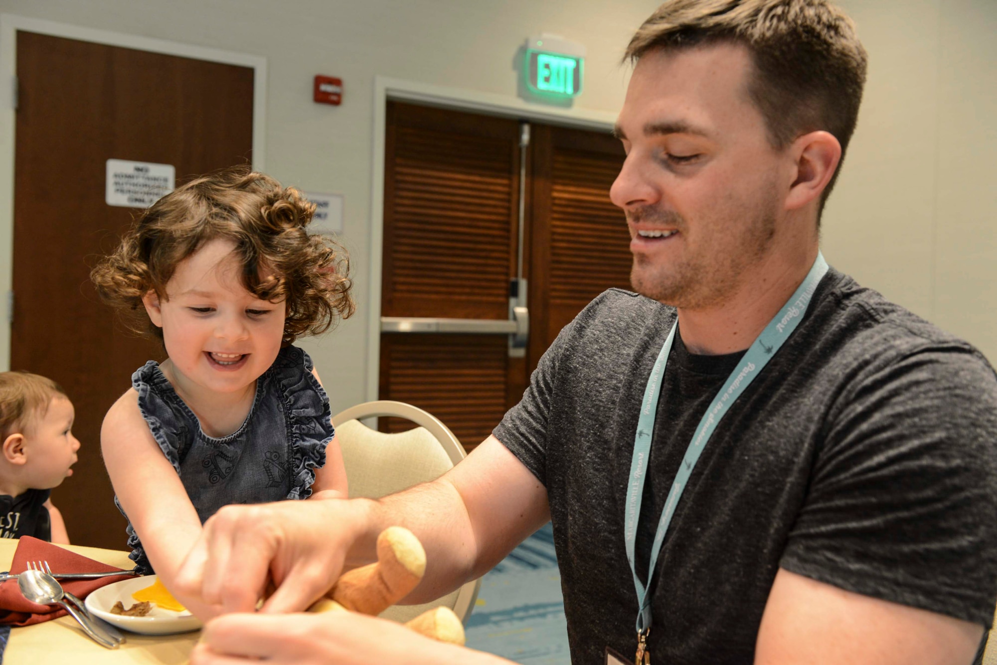 One person playing with their child while sitting at a table.