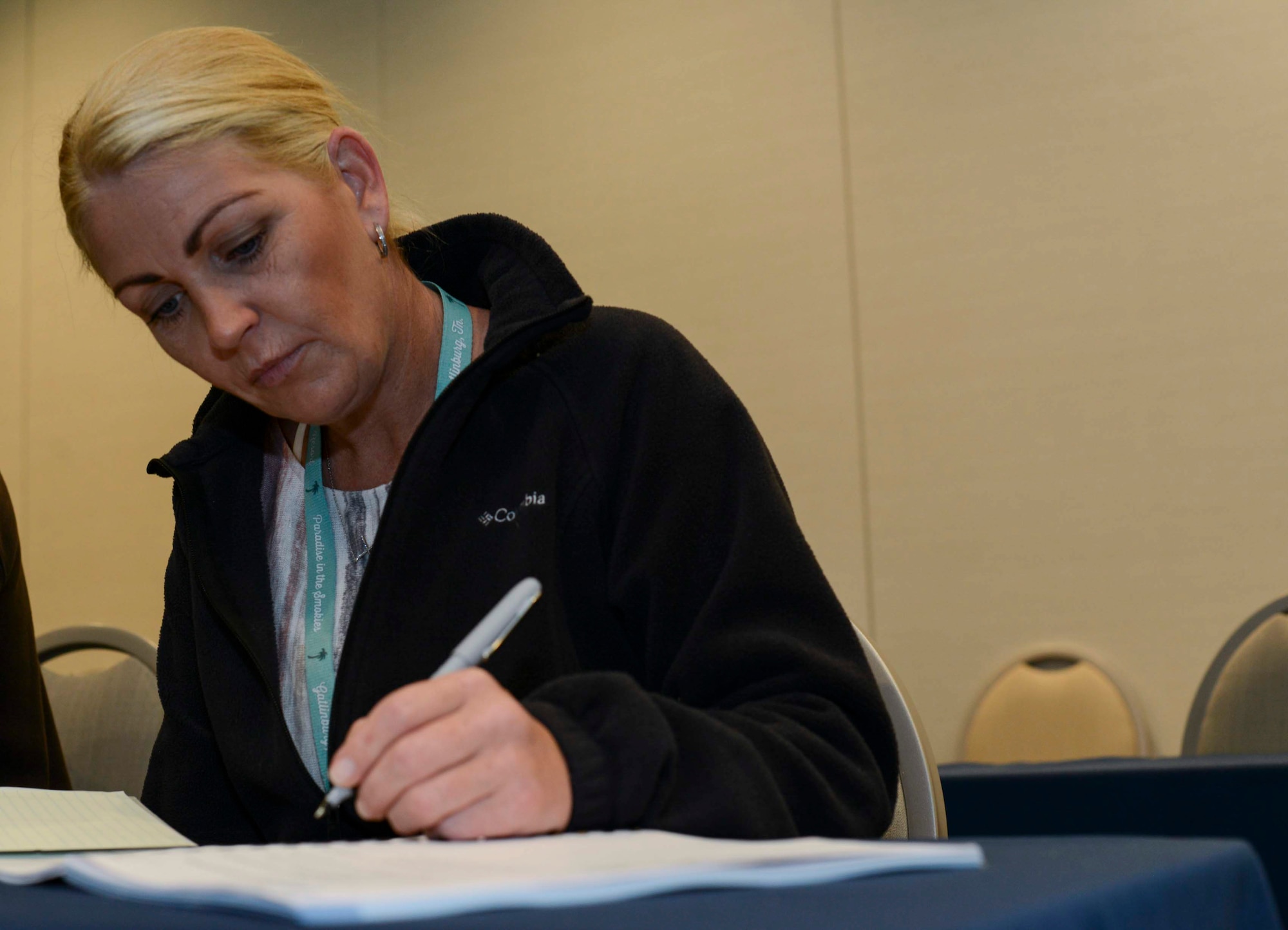 One person writing in a book while sitting at a table.