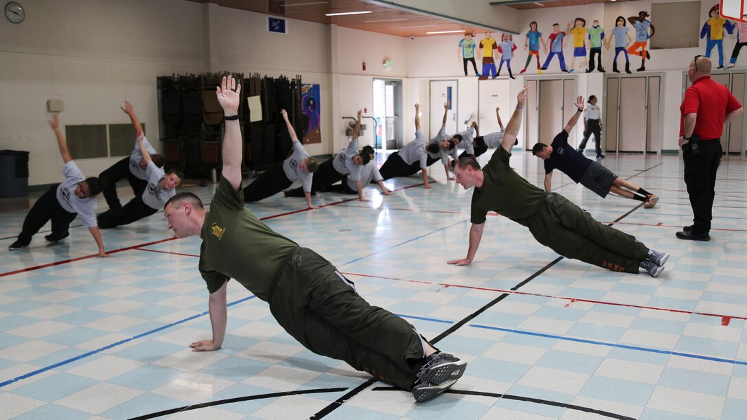 Sergeants Maxim Krymov and Kenneth Mullins from Marine Corps Logistics Base Barstow, exercise along with students they are mentoring through the SHOCK program at the Phoenix Academy in Apple Valley, Calif., April 19.