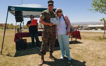 U.S. Marine Corps Brig. Gen. Roger B. Turner, commanding general, Marine Air Ground Task Force Training Command, Marine Corps Air Ground Combat Center, Twentynine Palms, Calif., presents Dawn Hicks with the Civilian Volunteer of the Year Award at Victory Field on the base April 24, 2019. The American Friends of our Armed Forces (AFAF) sponsored the award ceremony to show appreciation for AFAF volunteers and staff. (U.S. Marine Corps photo by Lance Cpl. Robin Lewis)