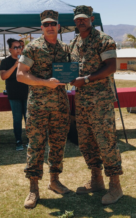 U.S. Marine Corps Brig. Gen. Roger B. Turner, commanding general, Marine Air Ground Task Force Training Command, Marine Corps Air Ground Combat Center, Twentynine Palms, Calif., presents U.S. Marine Staff Sgt. Shawndale Williams with the Service Volunteer of the Year Award at Victory Field on the base April 24, 2019. The American Friends of our Armed Forces (AFAF) sponsored the award ceremony to show appreciation for AFAF volunteers and staff. (U.S. Marine Corps photo by Lance Cpl. Robin Lewis)