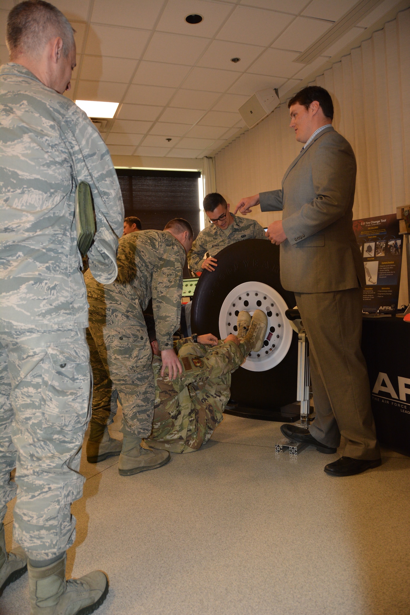 J.D. Bales, of the Air Force Research Laboratory, demonstrates the Air Force new C-5 tire changing tool to senior leaders from across the Air Force. The new tool requires two Airmen to change a tire with a tool adjustable in height and angle use on all tires with a faceplate designed for interoperability with all current spanner wrenches. The previous tool required five Airmen. The demo was part of an AFRL Tech Expo for the Basing and Logistics Board. (U.S. Air Force photo/Karen Schlesinger)