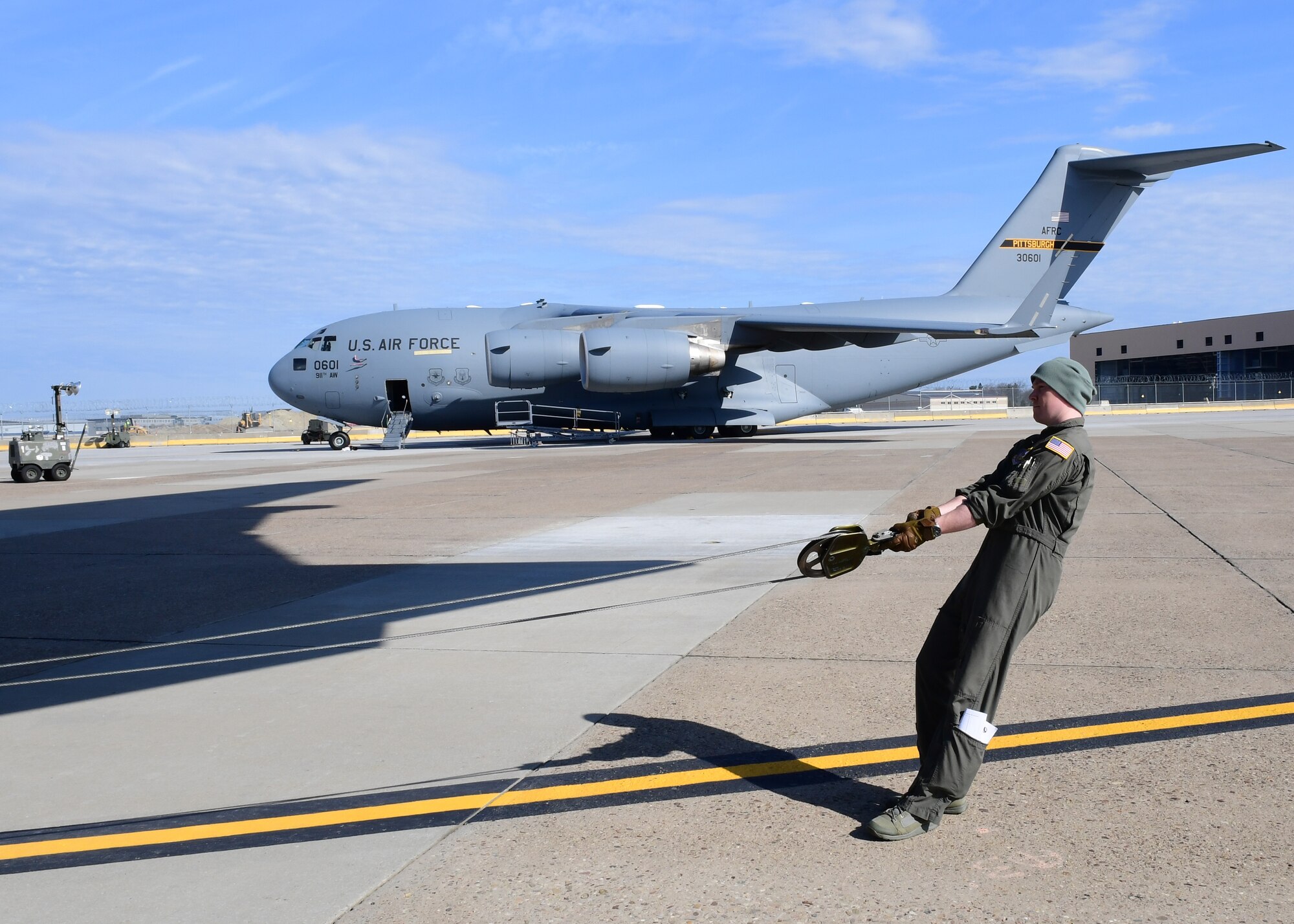 Tech. Sgt. Paul Maginnis, loadmaster with the 758th Airlift Squadron, checks the length of cable at the Pittsburgh International Air Reserve Station, Pennsylvania, April 11, 2019. Maginnis prepared the cable for the aircraft tug, which is used to move extremely heavy aircraft,  in order to ensure safe loading.(U.S. Air Force Photo by Senior Airman Grace Thomson)