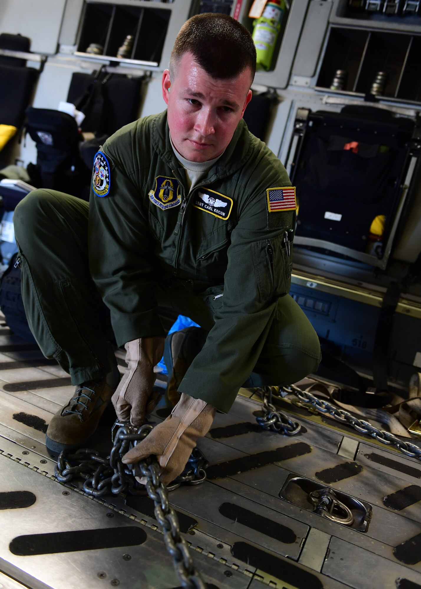 Staff Sgt. Carl Kocon, loadmaster attached to the 758th Airlift Squadron, uses heavy chains to tie down the aircraft tug, which is used to move extremely heavy aircraft, at Dobbins Air Reserve Base, Georgia, April 11, 2019. There were several points that the aircraft tug needed to be tied down by to ensure safe travel.(U.S. Air Force Photo by Senior Airman Grace Thomson)