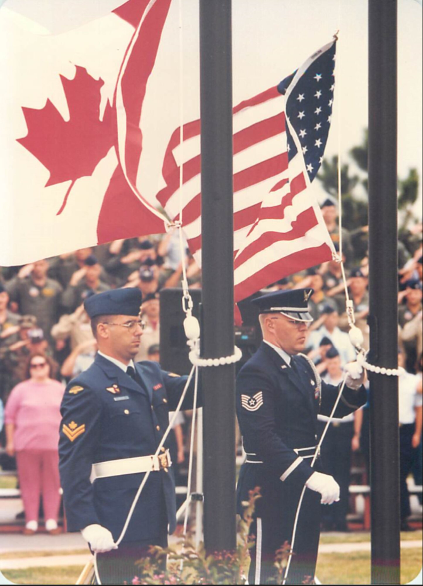 Members of the 552nd Air Control Wing and the Canadian Detachment raise their respective flags during a joint ceremony.