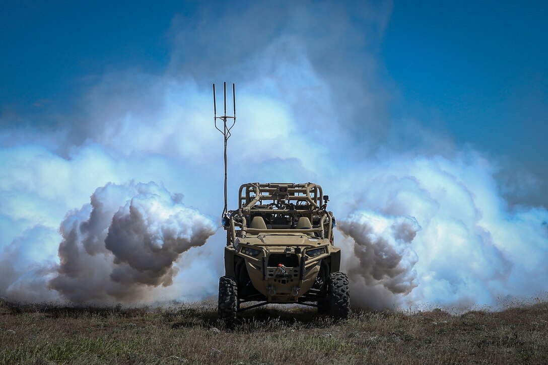 Clouds of vapor surround the sides and rear of a vehicle in a field.