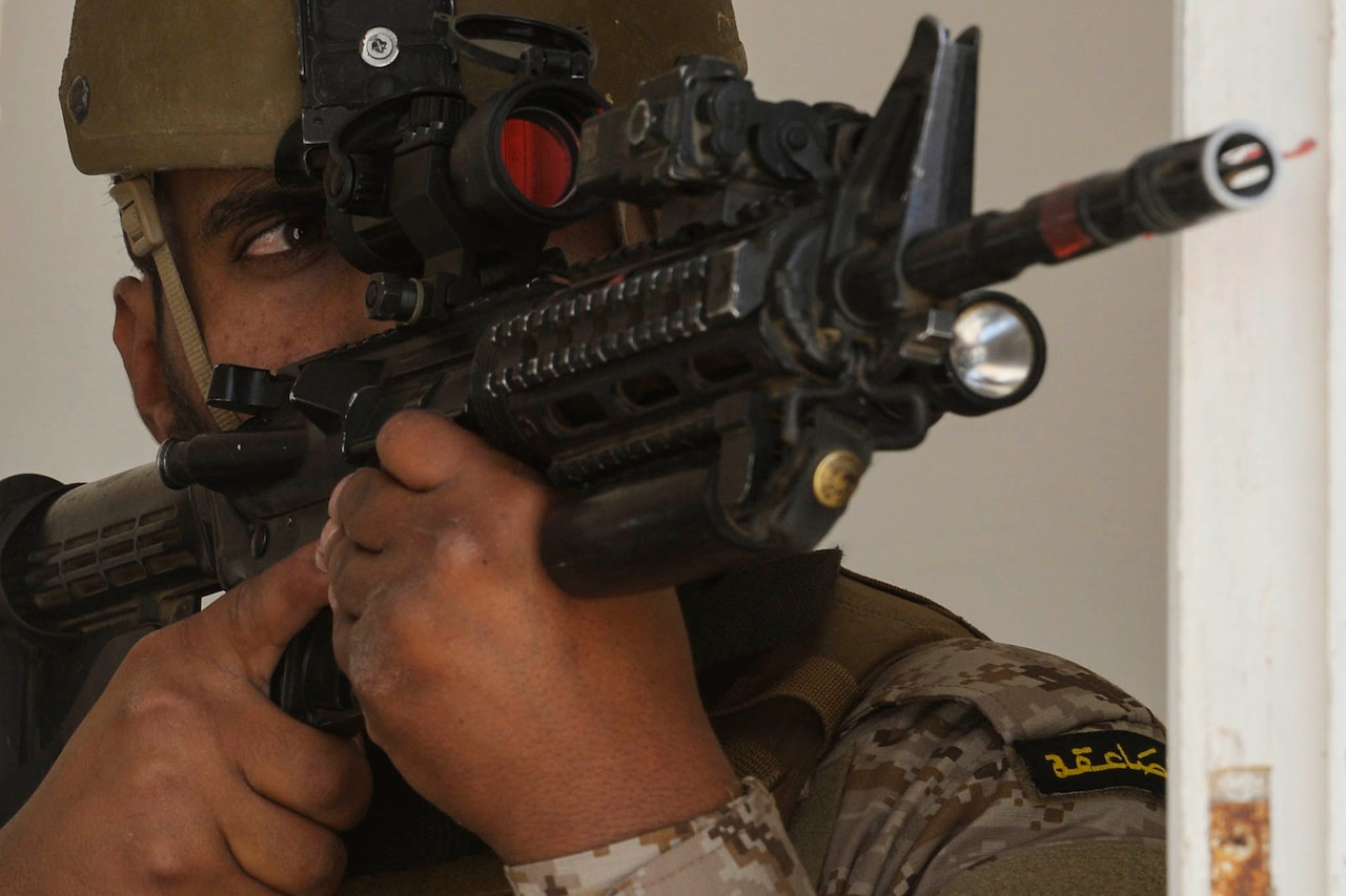 A service member looks through the scope on a rifle.