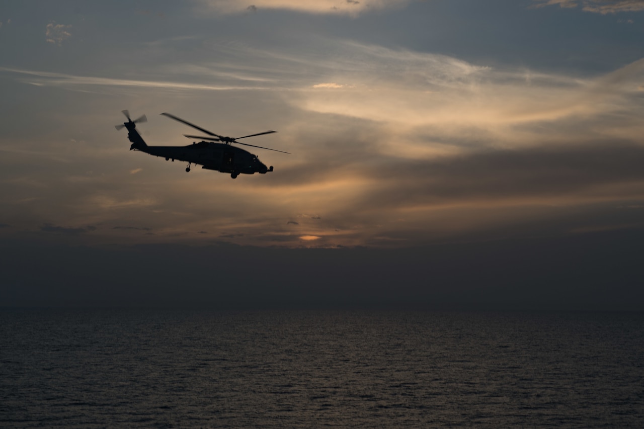A helicopter flies solo over the ocean.