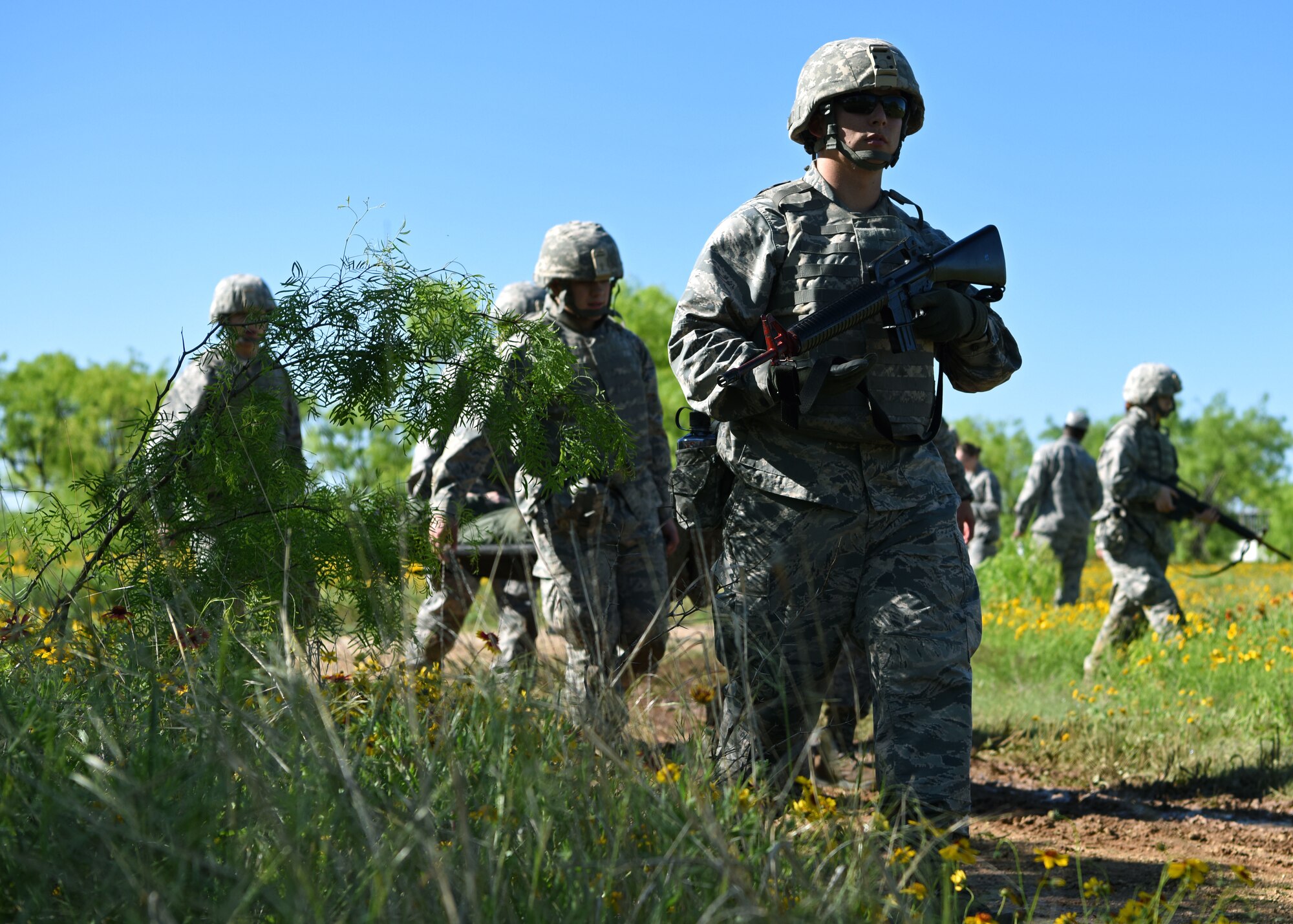 Angelo State University Air Force ROTC Cadets escort their injured wingman back to their forward operating base Camp Sentinel during their field training exercise at Goodfellow Air Force Base, Texas, April 25, 2019. The cadets marched in a wedge formation to allow immediate fire in all directions in case of an attack. (U.S. Air Force photo by Airman 1st Class Ethan Sherwood/Released)