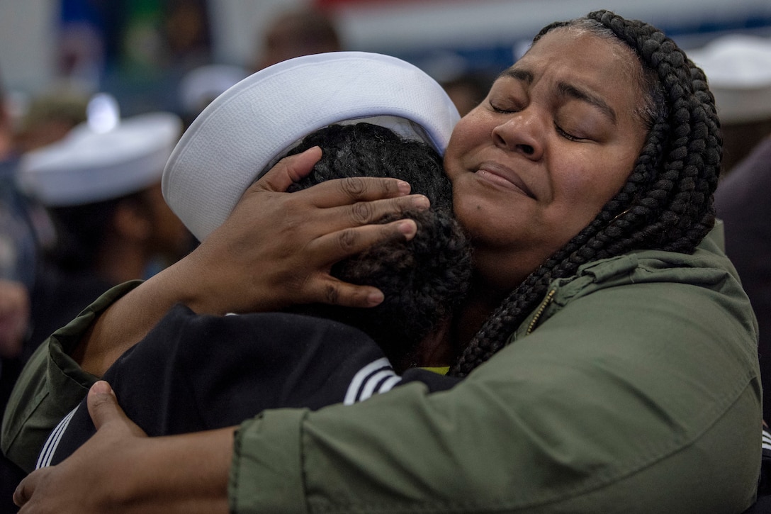 A woman embraces  a sailor.