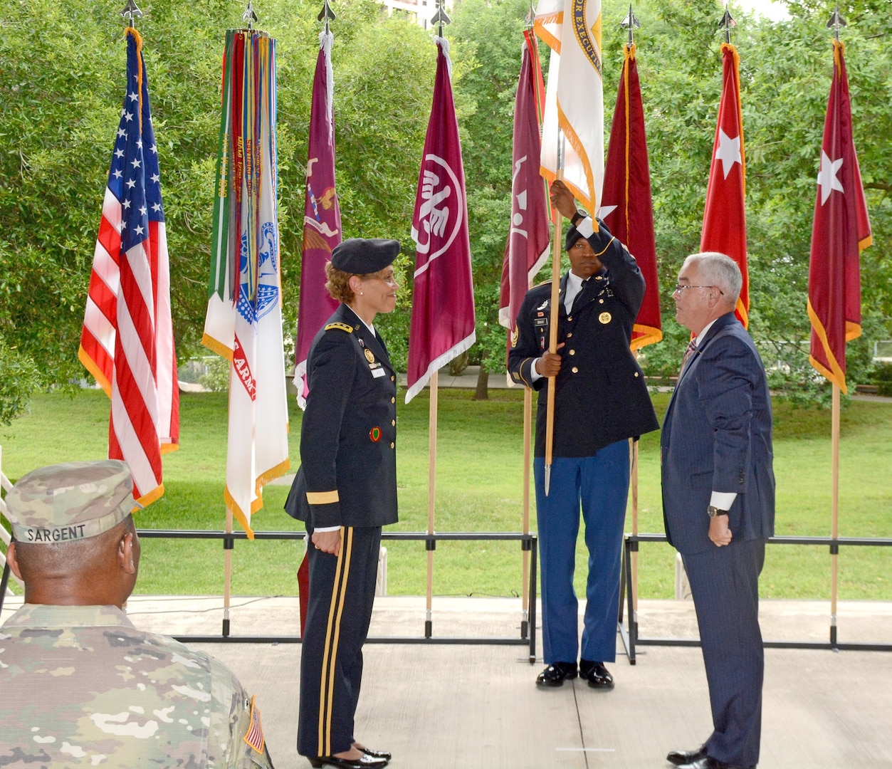 Command Sgt. Maj. Michael L. Gragg, MEDCOM Command Sergeant Major, unfurls the Senior Executive Service flag, as Lt. Gen. Nadja Y. West and Joseph M. Harmon III look on. Harmon was appointed to the Senior Executive Service in a ceremony at the Army Medical Department Museum April 29.
