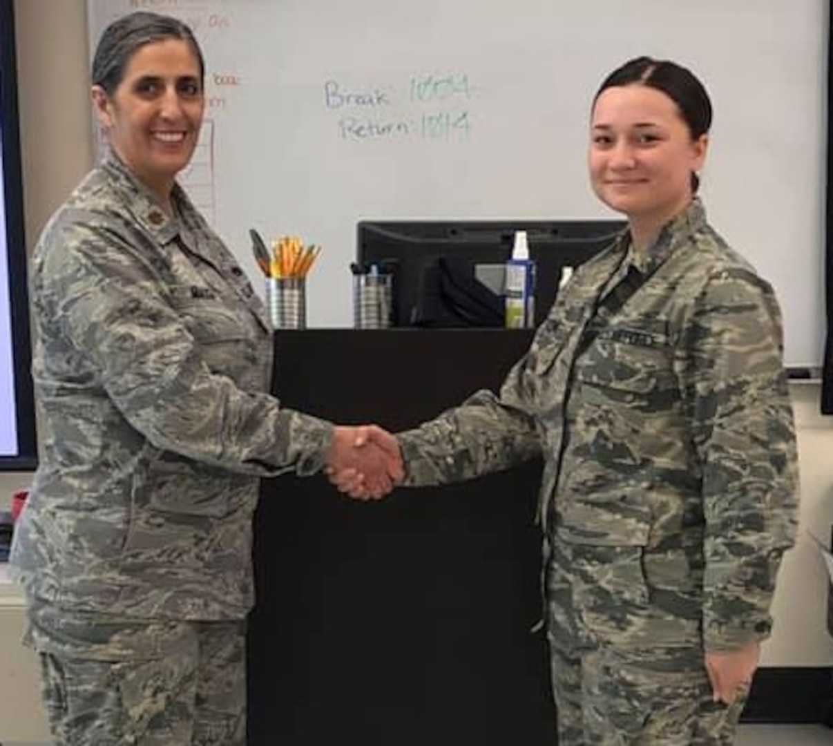 Maj. Brenda Miazga (left), Medical Education and Training Campus Aerospace Medical Service Apprentice program department chair, presents Airman Grace Dawson with a challenge coin for her actions during a medical emergency.