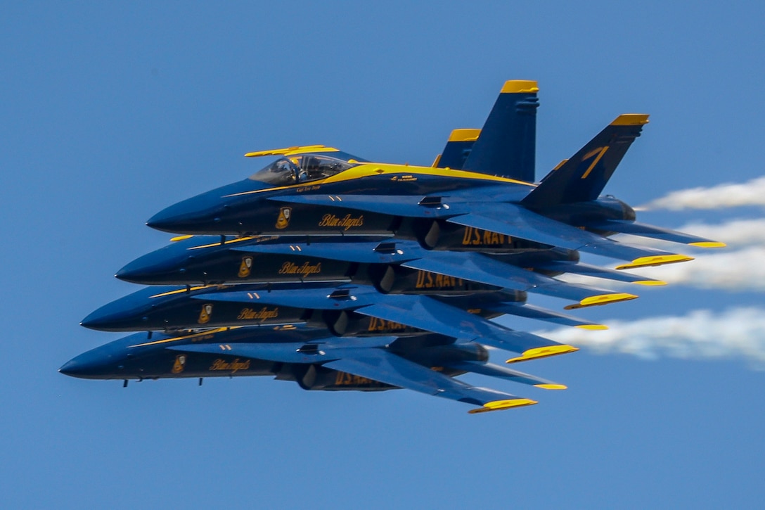 Four fighter jets fly in a tight formation across the sky, leaving trails of exhaust behind them.