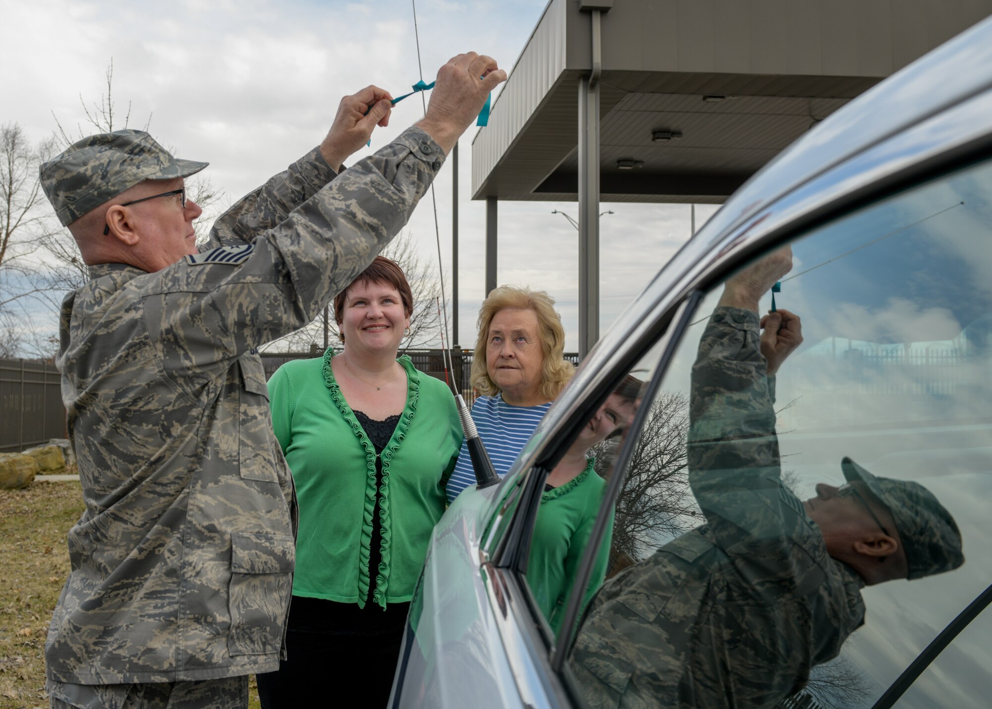 Master Sgt. Daniel Barninger, first Sgt. for the 910th Security Forces Squadron, ties a teal ribbon to a police cruiser here.