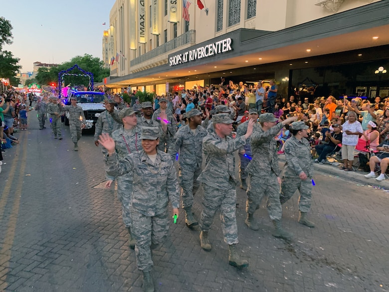 Reserve Citizen Airmen from the 433rd Airlift Wing and 960th Cyberspace Wing wave to parade goers on Broadway St. in downtown San Antonio during the 71st annual Fiesta Flambeau Parade, April 27, 2019.