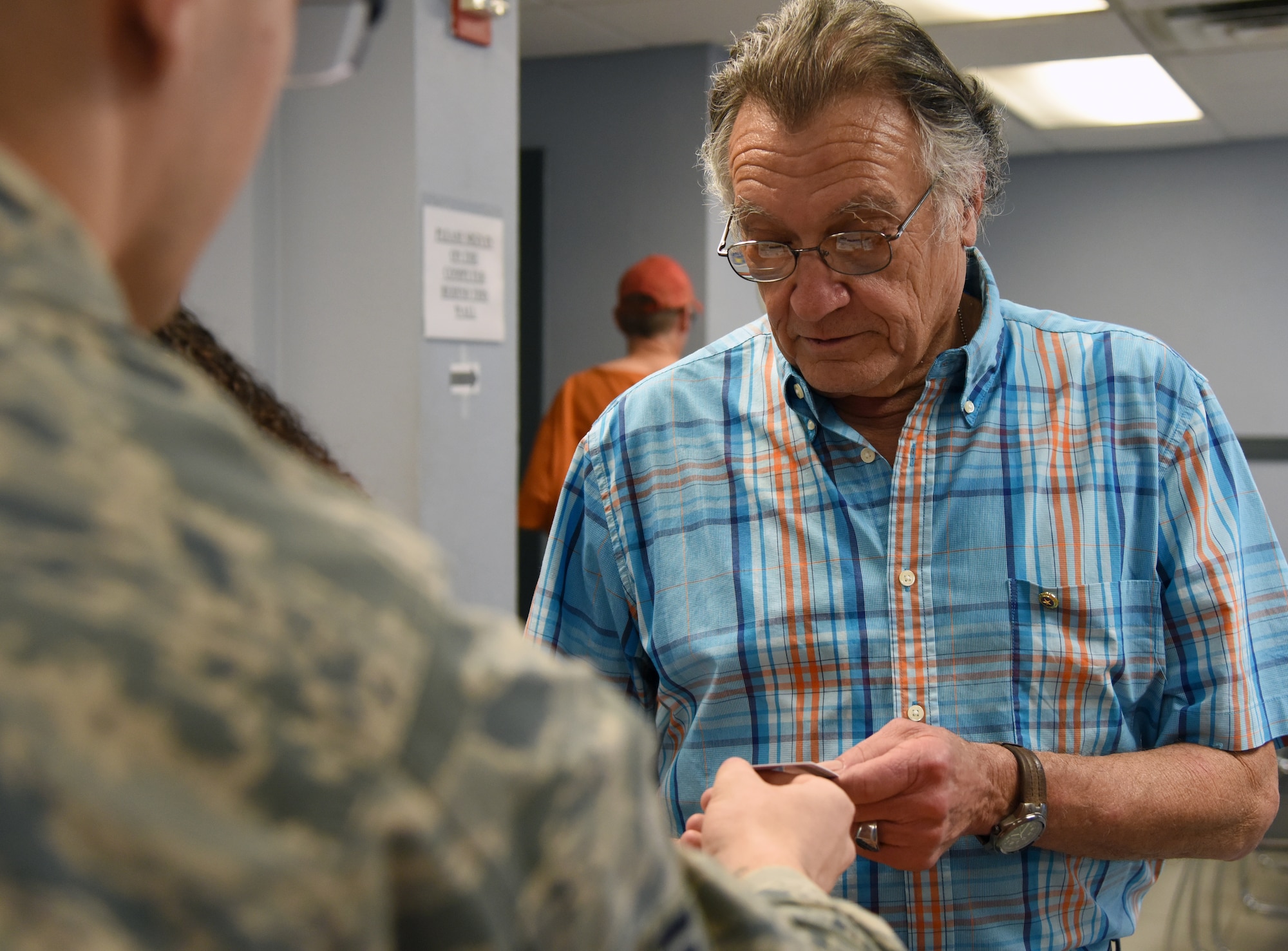 U.S. Air Force Senior Airman Shayne Hopkins, 81st Security Forces Squadron visitor control center clerk, presents Ashton Belcher, brother of Maj. Robert Belcher, with his Gold Star Family Member ID card inside the Visitors Center at Keesler Air Force Base, Mississippi, April 26, 2019. Robert was an F-4 pilot who served during the Vietnam War and was placed in POW/MIA status following his disappearance while on a mission to mark targets in 1969. As a surviving brother of a POW/MIA service member, Ashton is allowed to obtain a Gold Star Family Member ID card for recognition and installation access so that he can attend events and access Airman & Family Readiness Center referral services. (U.S. Air Force photo by Kemberly Groue)