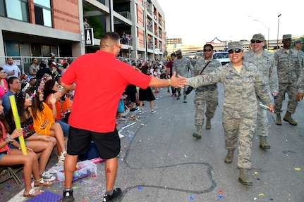 Tech. Sgt. Nelida Balderas, 433rd Operational Support Squadron aircrew flight equipment technician, high-fives a fan during the 71st annual Fiesta Flambeau Parade April 27. Balderas was escorting the 433rd Airlift Wing's and 960th Cyberspace Wing’s “"Reflections of Music Past” themed float that was seen by over 750,000 spectators lining the 2.6-mile-long route on the downtown streets of San Antonio.