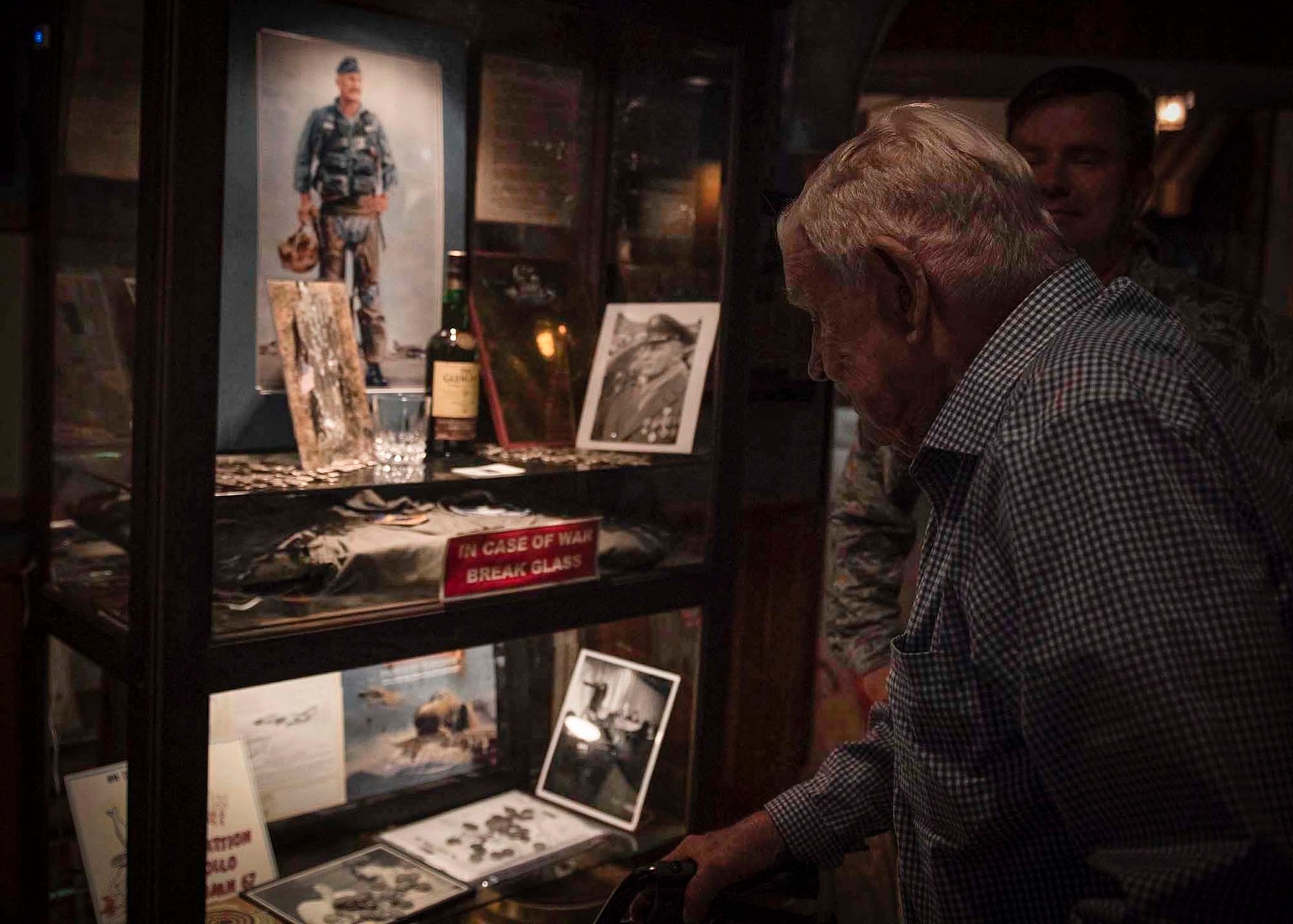 A retiree looks at a glass case filled with items representing the Air Force's heritage.