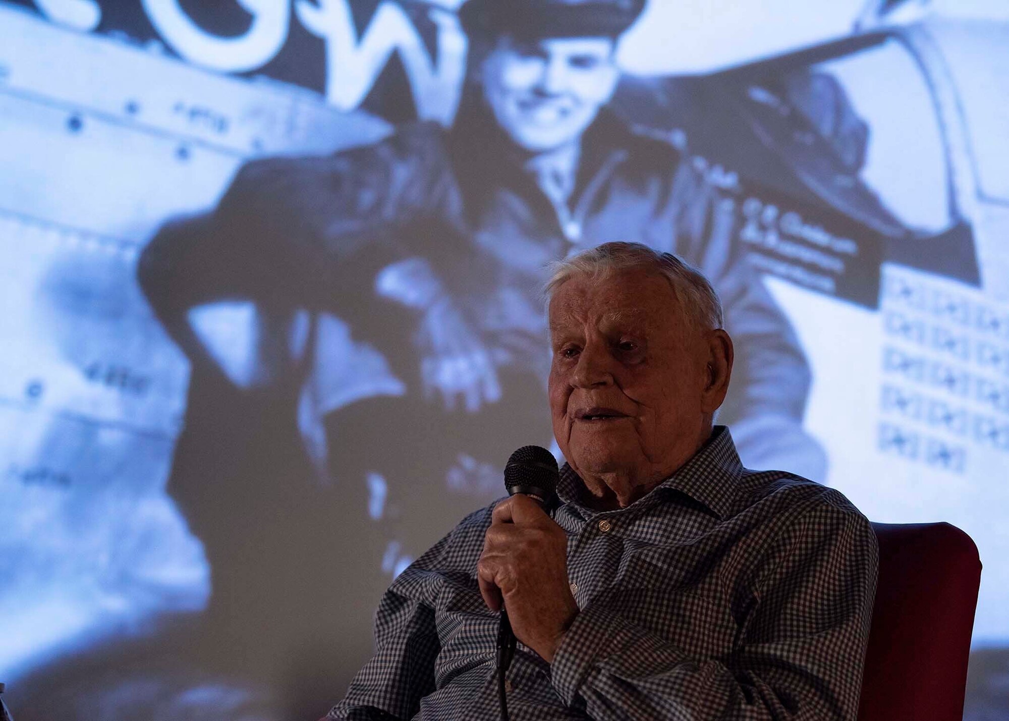 An Army Air Corps retiree holds a microphone.