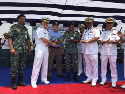 190425-N-ZZ999-001 CHITTAGONG, Bangladesh (April 25, 2019) Rear Admiral Joey Tynch, commander, Logistics Group Western Pacific, left, presents a symbolic key to Bangladesh Navy senior delagates during a ceremony at the Special Warfare Diving and Salvage (SWADS) Headquarters in Chittagong. Five metal patrol boats were handed over to the Bangladesh Navy and a ceremony was held commemorating the exchange of the crafts and celebrating the long-standing partnership between both nations. (Courtesy photo by Lt. Col. Matthew A. Kohler)