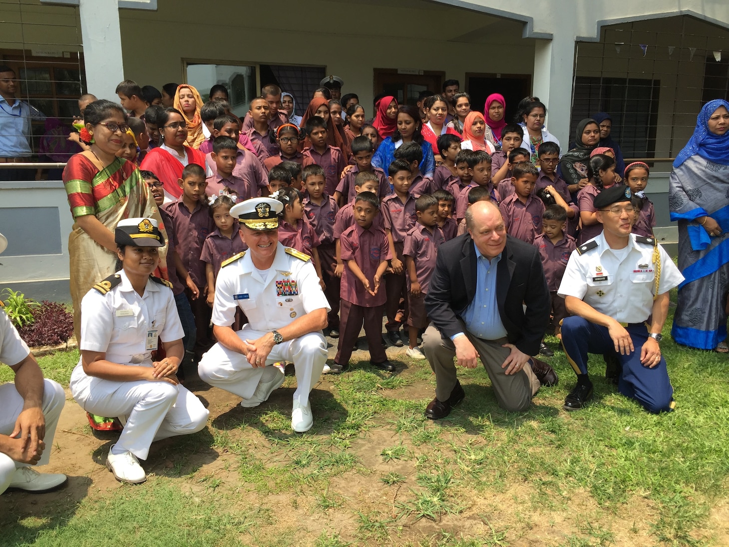 CHITTAGONG, Bangladesh (April 25, 2019) Rear Admiral Joey Tynch, commander, Logistics Group Western Pacific, and Joel Reifman, U.S. Deputy Chief of Mission to Bangladesh, pose for a photo with U.S. representatives and local students at Ashar Alo primary school. Tynch visited Ashar Alo, a school financed and directed by the Bangladesh Navy for special needs children, following a ceremony commemorating the exchange of five metal patrol boats and celebrating the long-standing partnership between both nations.