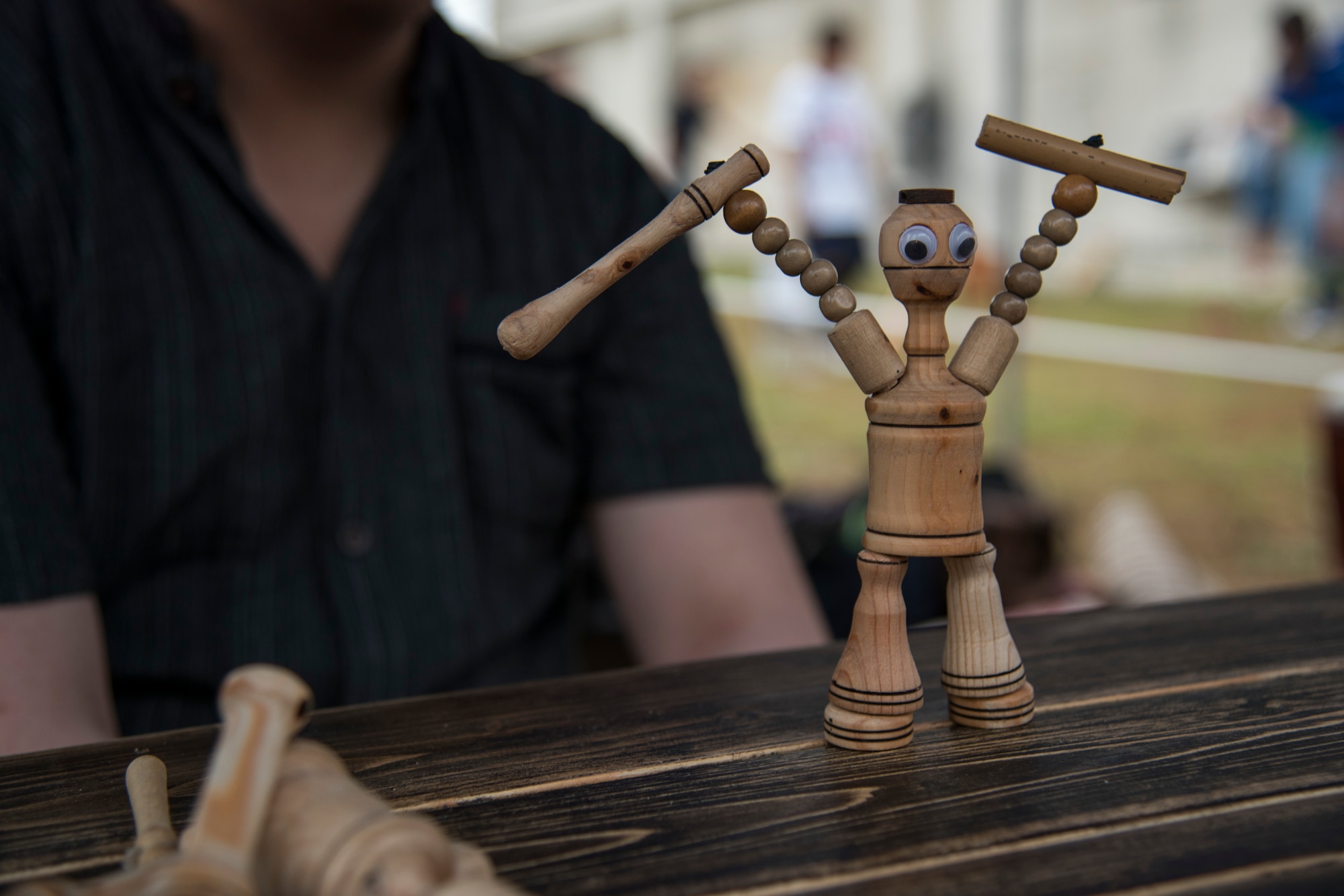 An action figure, ‘Mokko Fighter,’ stands on a table during the Tanabata Festival in Misawa City, Japan, July 26, 2019. The user controls the wooden figure’s arms and legs to simulate a dancing or fighting performance for guest. This attraction compares to a modern-day puppet show. (U.S. Air Force photo by Branden Yamada)
