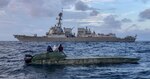 USS Michael Murphy's in the water next to a low profile vessel.