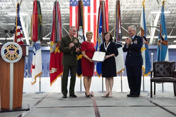 Mrs. Ricki Selva, center-right; poses for a photo with Mrs. Ellyn Dunford, center-left; after receiving the Spouse Award for Distinguished Public Service, as their husbands Marine Corps Gen. Joe Dunford, chairman of the Joint Chiefs of Staff, and Air Force Gen. Paul J. Selva, vice chairman of the Joint Chiefs of Staff, applaud during Gen. Selva's Retirement ceremony hosted at Hanger 3, Joint Base Andrews, Md., July 31, 2019. Gen. Selva retires after over 39 years of service.