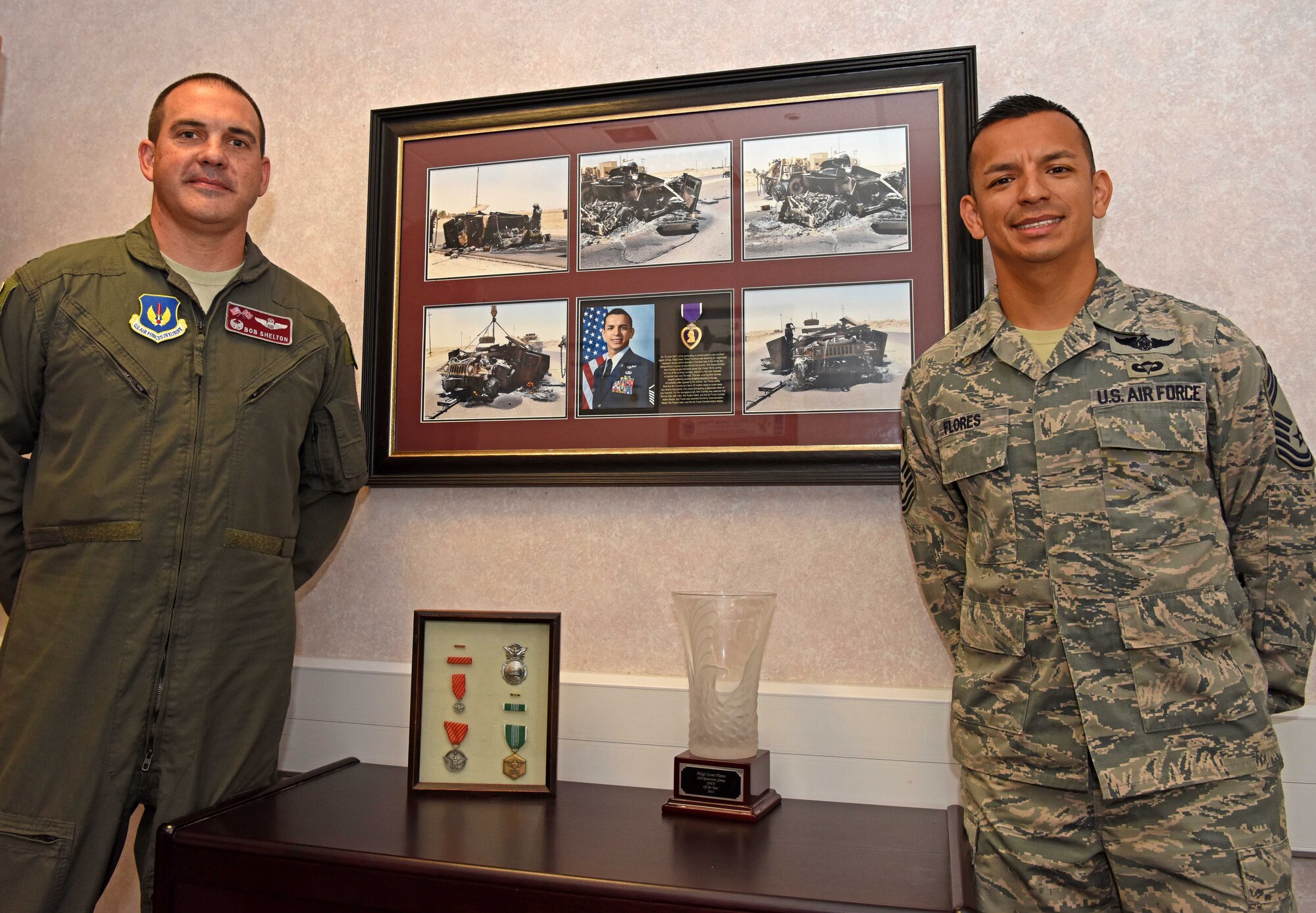Colonel Robert Shelton, 100th Operations Group commander, left, and Chief Master Sgt. Cesar Flores, 100th OG superintendent, pose for a photo with Flores’ Purple Heart plaque at RAF Mildenhall, England, July 24, 2019. Flores was awarded the Purple Heart and a wounded warrior designation after an armored vehicle he was in was struck by an improvised explosive device while deployed in Iraq in 2007. (U.S. Air Force photo by Airman 1st Class Brandon Esau)