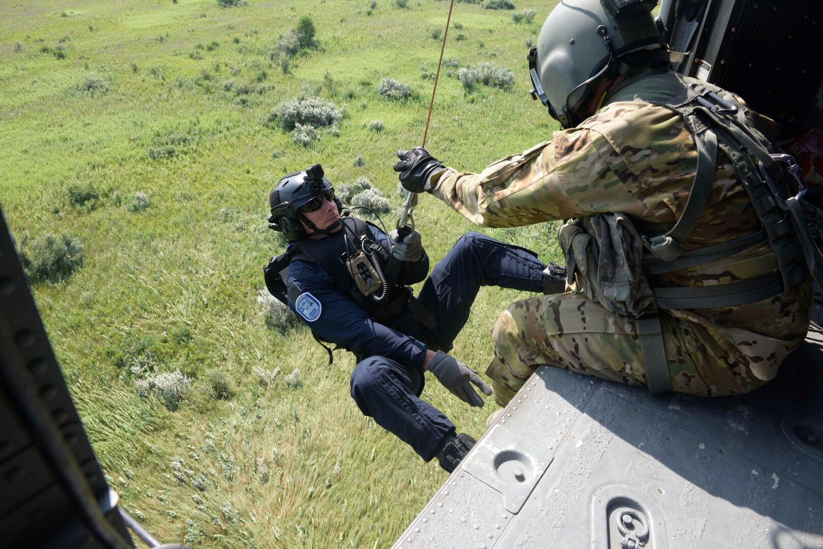 Sgt. Todd D. Overbeck, with C Company, 238th General Support Aviation Battalion, assists Brent VanBruaene, with the South Bend Fire Department, as he boards a UH-60 Black Hawk during hoist operations at Kingsbury, Indiana, July 23, 2019. Overbeck and VanBuraene are members of the Indiana Helipcopter Aquatic Rescue Team, a small team of National Guard members and firefighters with the South Bend fire Department.