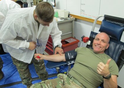 Army Spc. Joshua Gerstenberger, Fort Leonard Wood Blood Donor Center lab tech, prepares Army Maj. Gen. Frank Muth, Army Recruiting Command commanding general, to donate blood July 19. During the five-hour drive, 44 headquarters people donated to the Armed Services Blood Program. (Photo by Carl Norman).