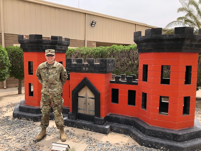 ROTC cadet in military uniform standing in front of a red castle, a symbol of the U.S. Army Corps of Engineers.