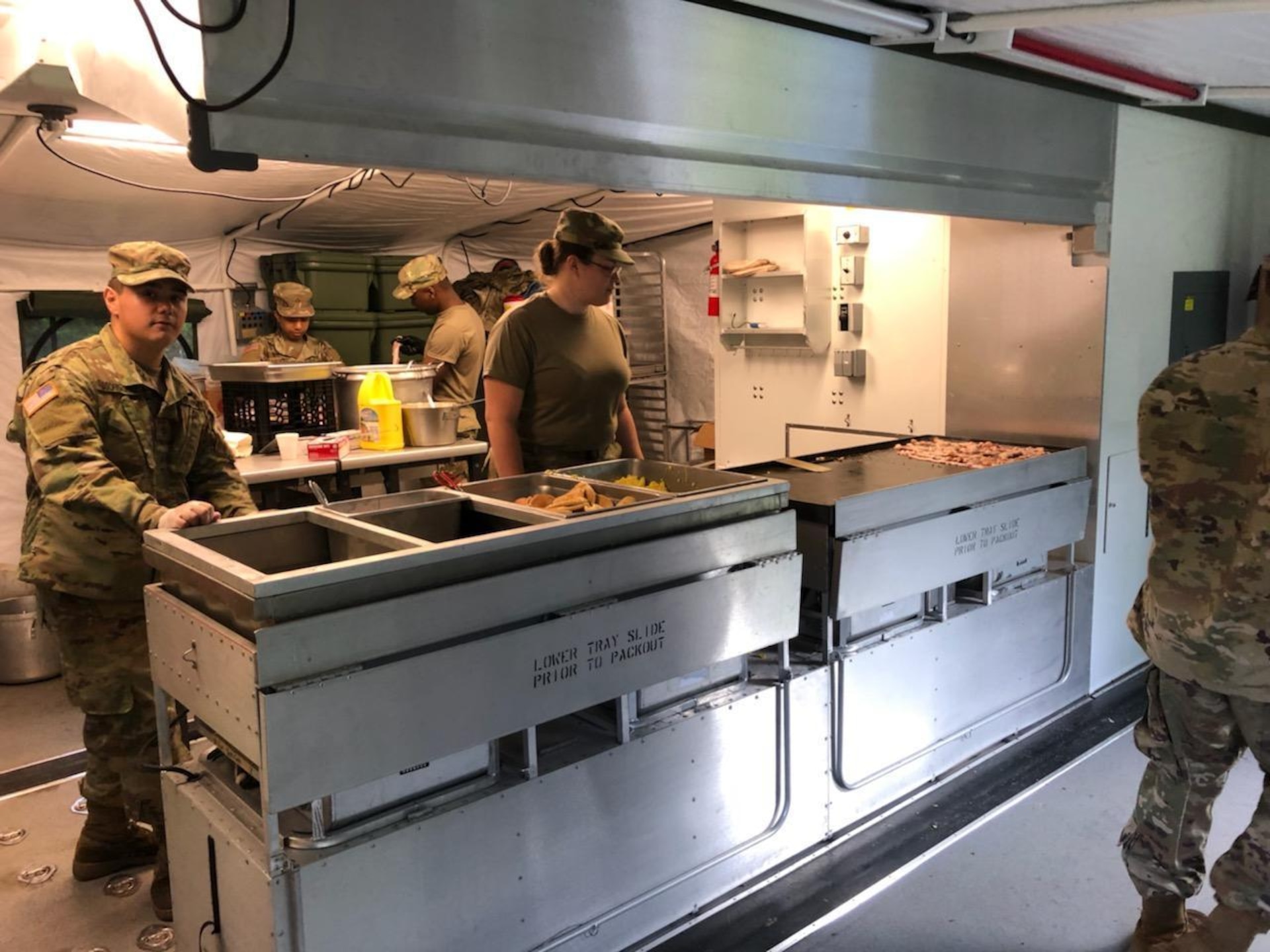 New York Army National Guard Pfc Delmar Osorio-Ortiz and Pfc Amber Vaneywick, assigned to the 642nd Aviation Support Battalion, prepare the dinner meal in the Containerized Kitchen as part of the field training exercise on July 27th during annual training at Fort Indiantown Gap, Pa. The Connelly Competition evaluation incorporates both the preparation of the meal and the serving.