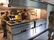 New York Army National Guard Pfc Delmar Osorio-Ortiz and Pfc Amber Vaneywick, assigned to the 642nd Aviation Support Battalion, prepare the dinner meal in the Containerized Kitchen as part of the field training exercise on July 27th during annual training at Fort Indiantown Gap, Pa. The Connelly Competition evaluation incorporates both the preparation of the meal and the serving.