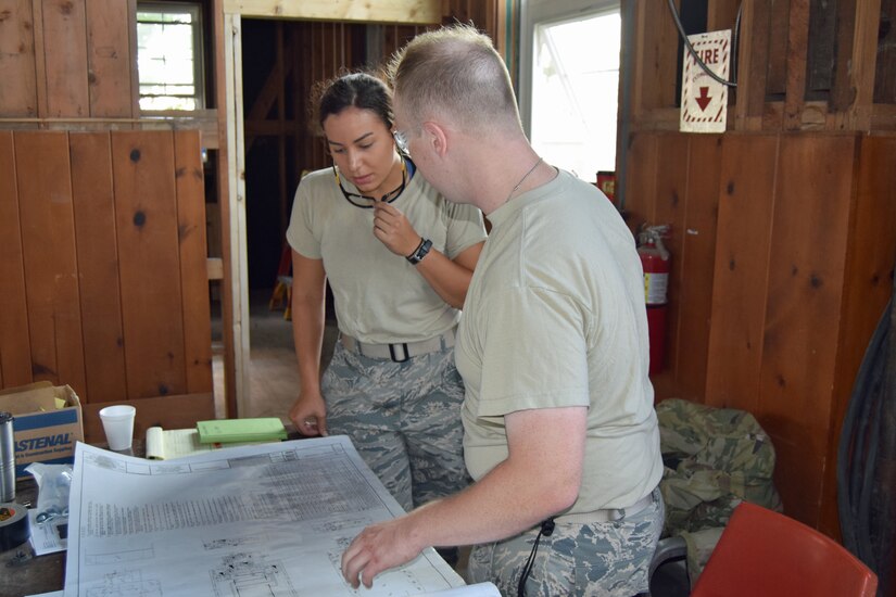 Airman 1st Class Mya Bellinger and Staff Sgt. Kevin Krokosky, 127th Civil Engineering Squadron electricians, study a blue print during a renovation project at Fort Indiantown Gap National Guard Training Center, Annville, Pennsylvania, on July 22, 2019.