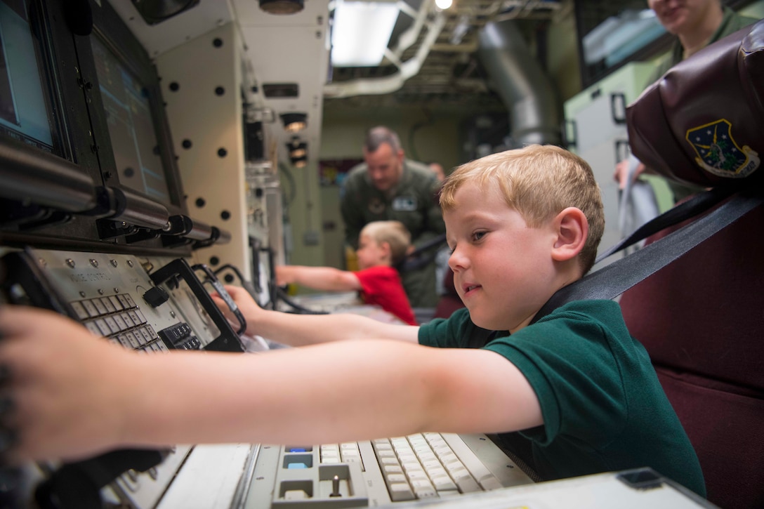 A child sits at a desk with a lot of buttons on the desk.